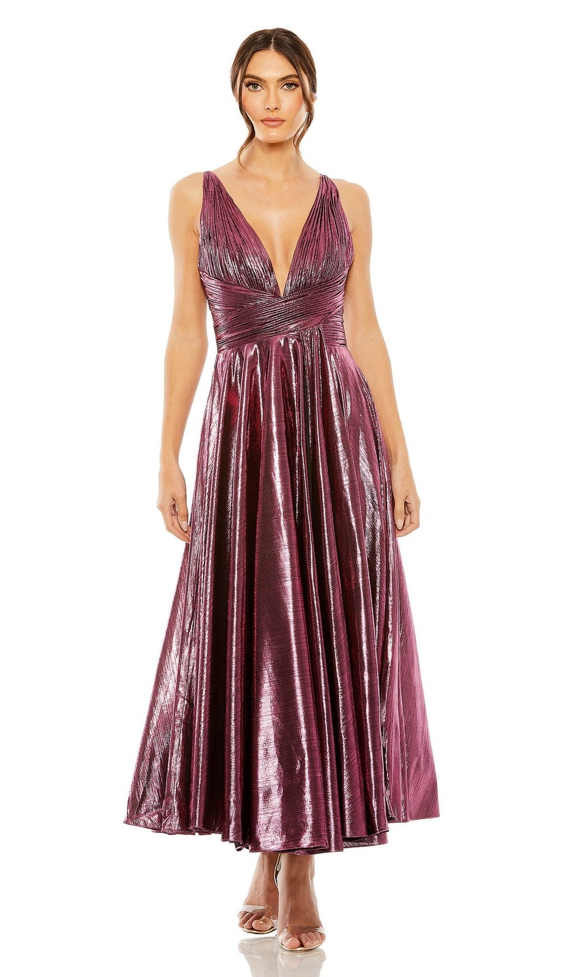 A woman wears the Mac Duggal 30761 tea-length wedding-guest dress, featuring a sleeveless metallic magenta design with a deep V-neckline and pleated skirt, paired with nude heels.